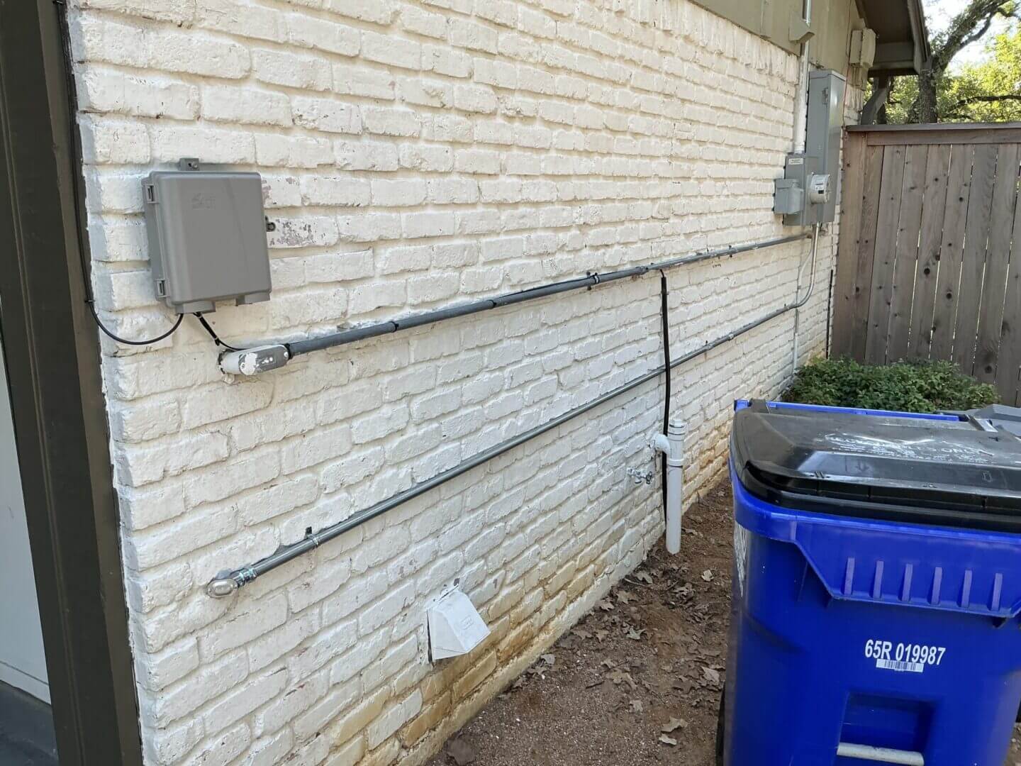 White brick wall with electrical boxes outside.
