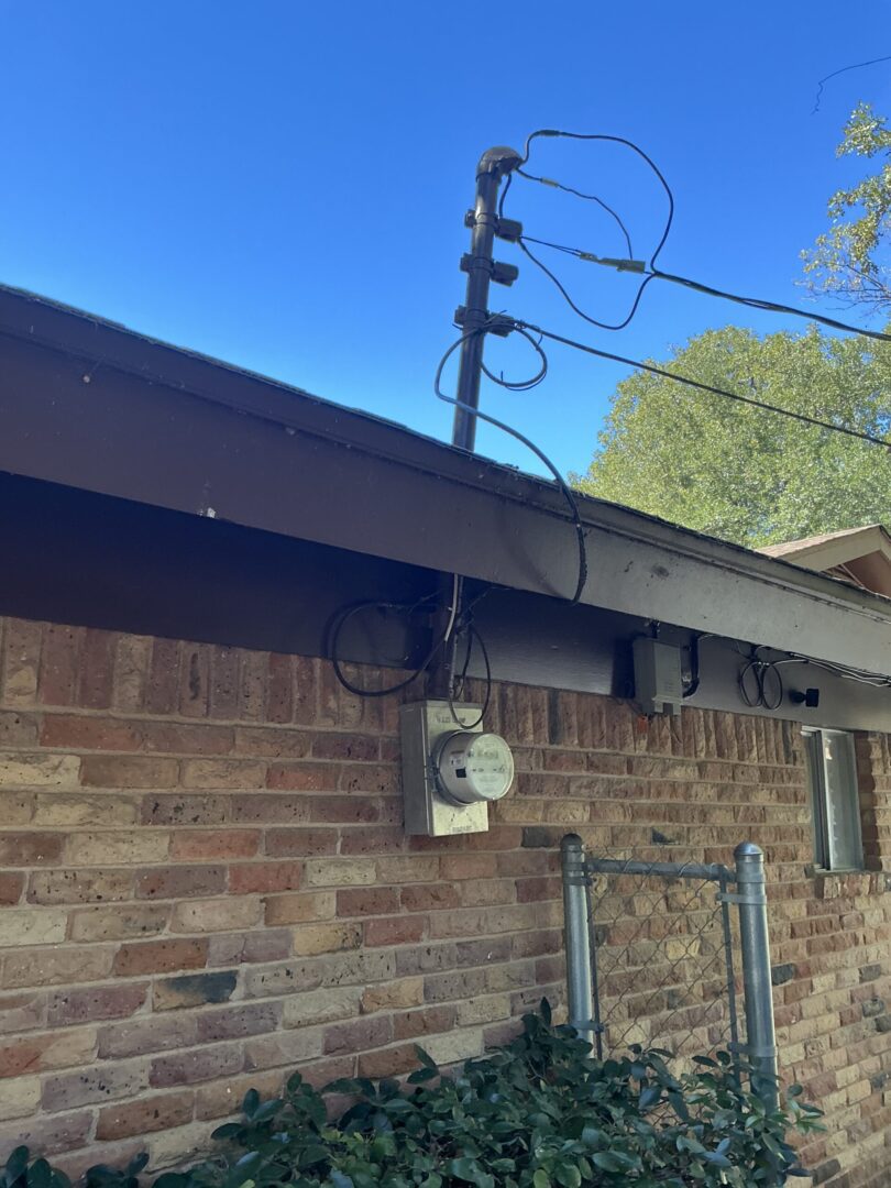 Brick house with electrical meter and wires.