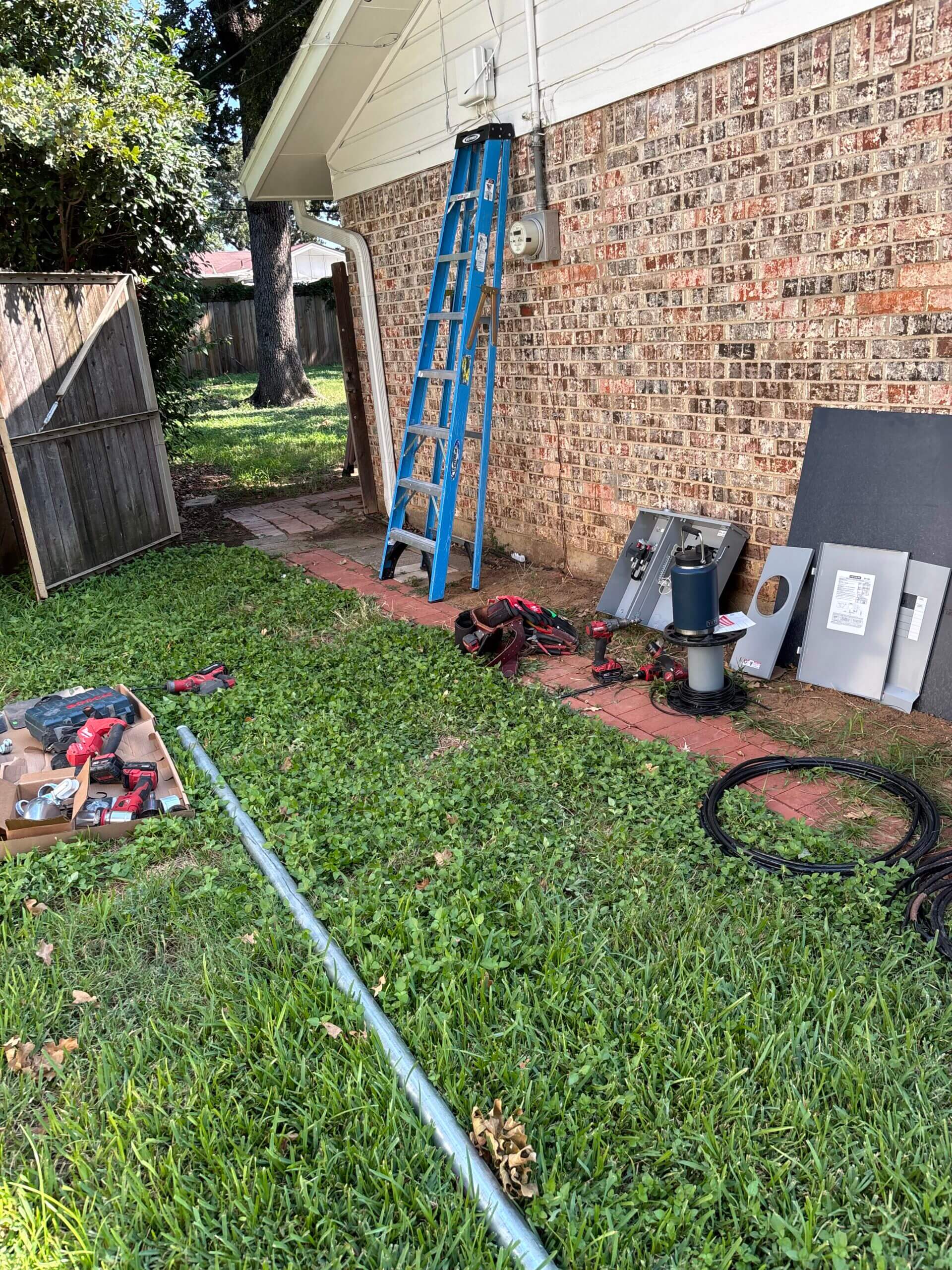 Ladder and tools near a brick wall.
