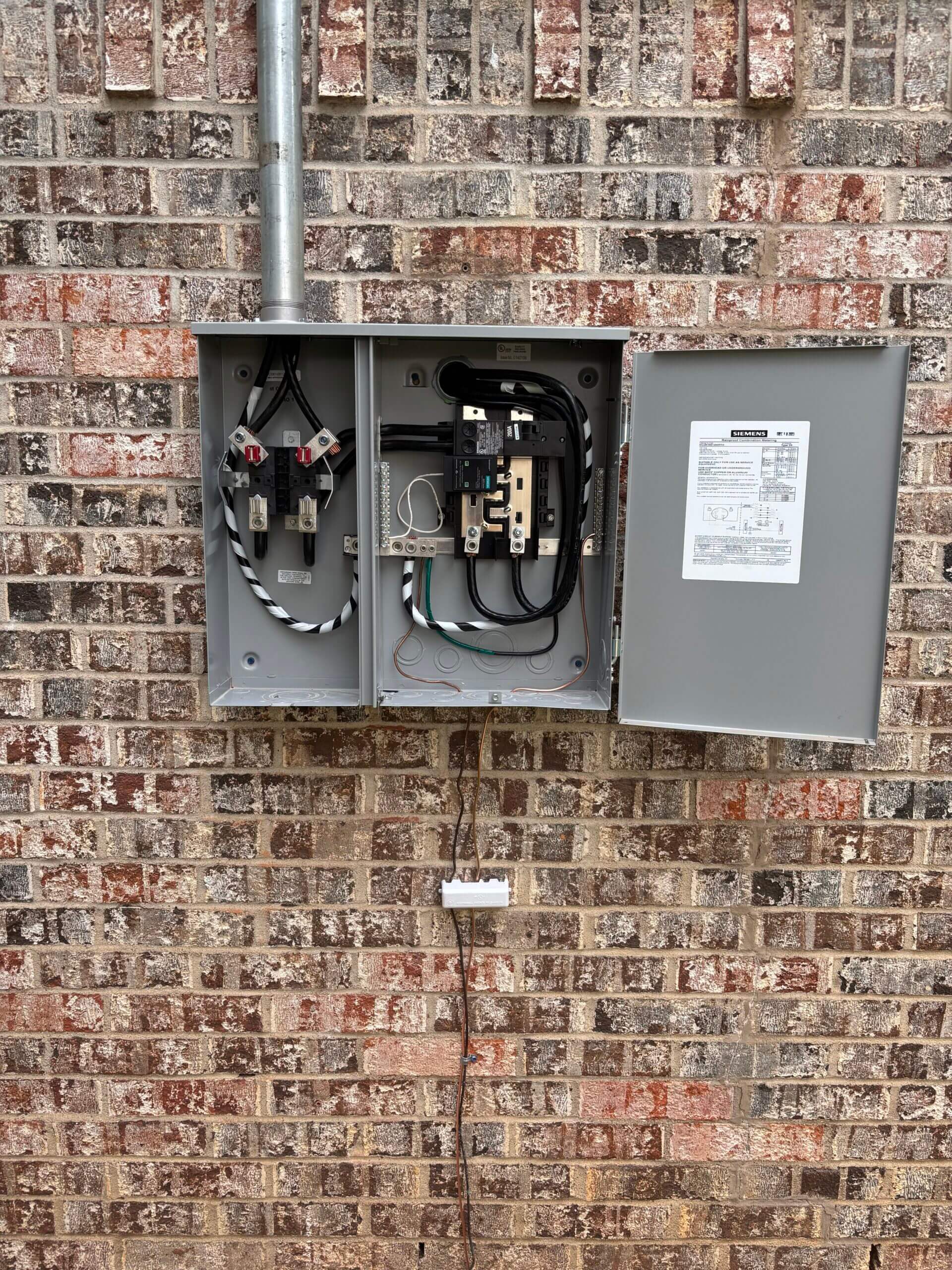 Electrical box on brick wall, door open.