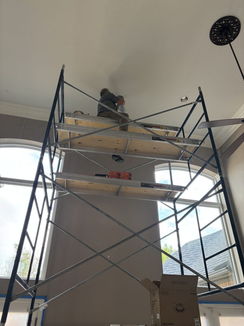 Worker on high indoor scaffolding platform.